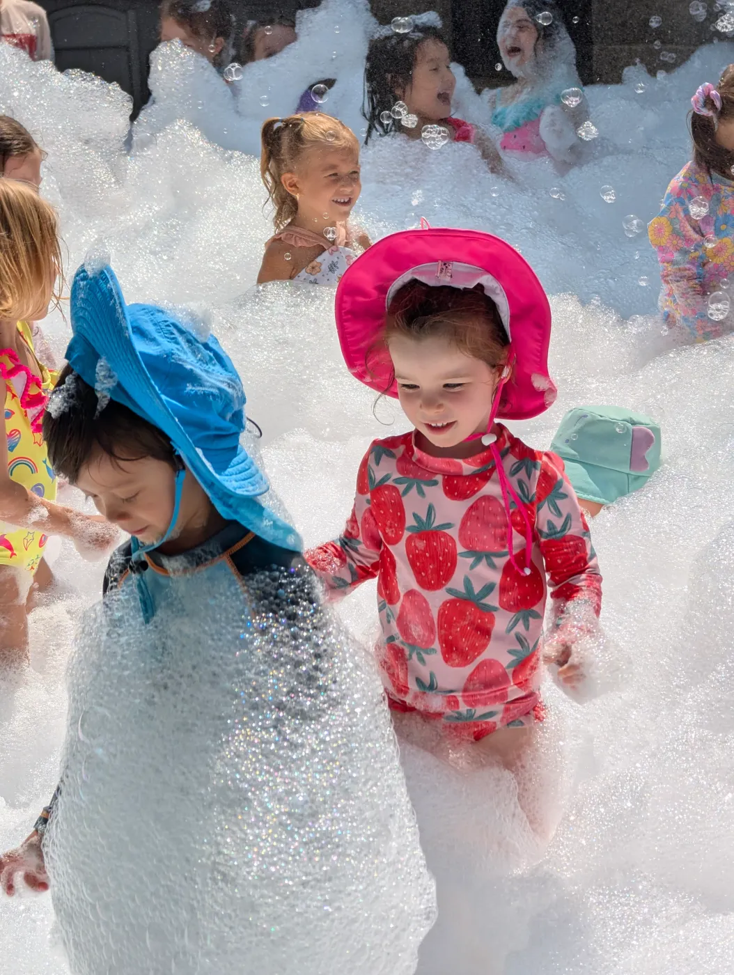 Children in colorful hats playing in foam
